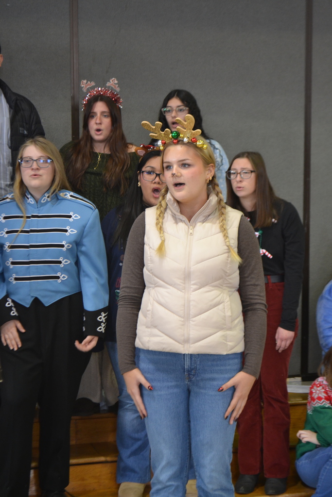 Image contains female student singing a solo in front of other choir members during the holiday conert.