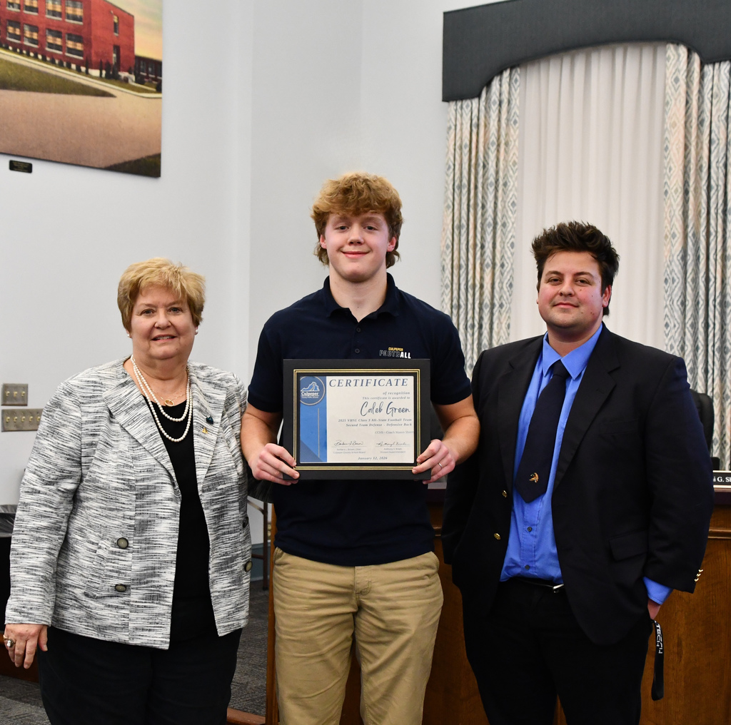 student holding certificate with coach and board member in board room