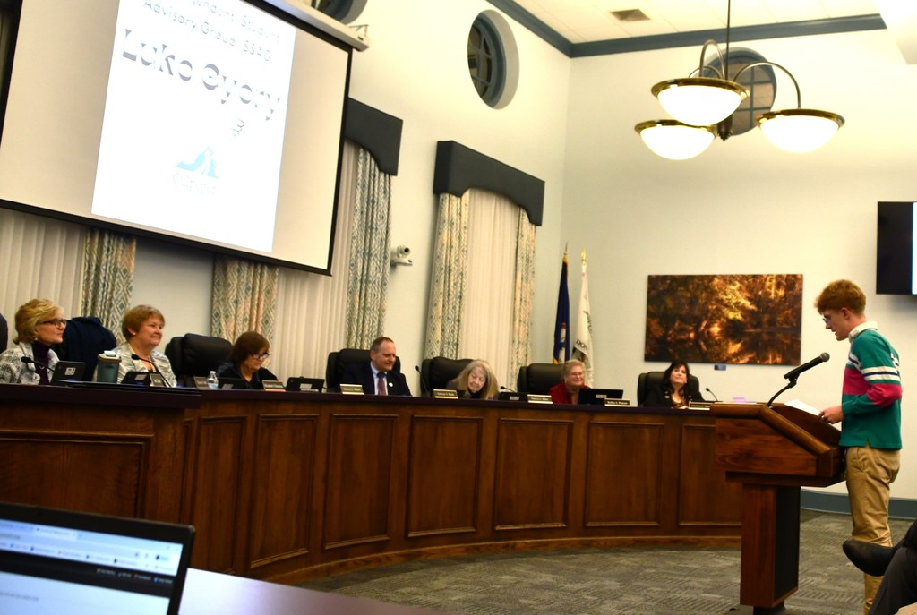 student speaking at the podium to the school board while the board listens