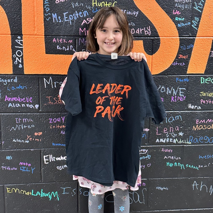 Girl holding a Leader of the Pack T-shirt in front of a colorful wall