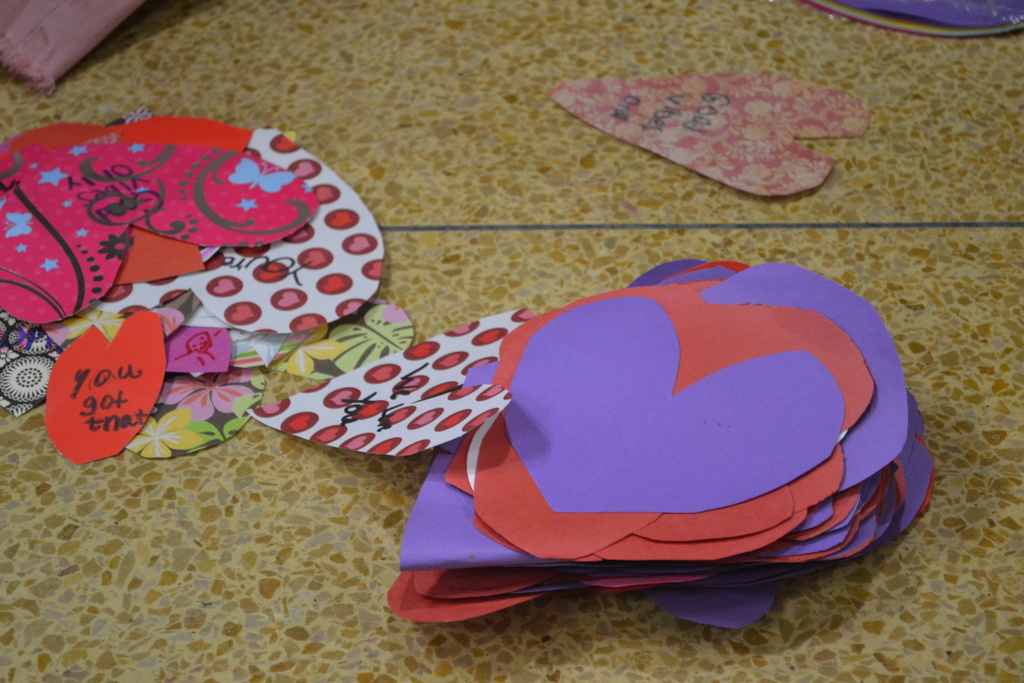 Image contains a pile of cut out hearts  on the school floor.