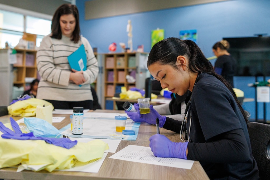 CTEC medical assistant student performs a medical lab test while an industry partner observes during Skills Showcase in a clinical training classroom.