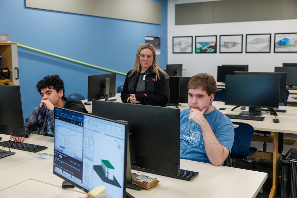 CTEC students work at computers on design software while an industry partner observes in a computer lab.