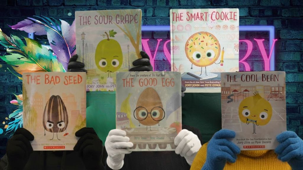 “Five people stand in front of a brick wall with a neon sign partially visible behind them, each holding a children’s book in front of their face so their identities are hidden. The books shown are The Bad Seed, The Sour Grape, The Good Egg, The Smart Cookie, and The Cool Bean by Jory John and Pete Oswald. The colorful covers feature cartoon food characters, including a sunflower seed, grape, egg with glasses, cookie with sprinkles, and bean. Only the readers’ gloved hands and parts of their clothing are visible while they hold the books up.”