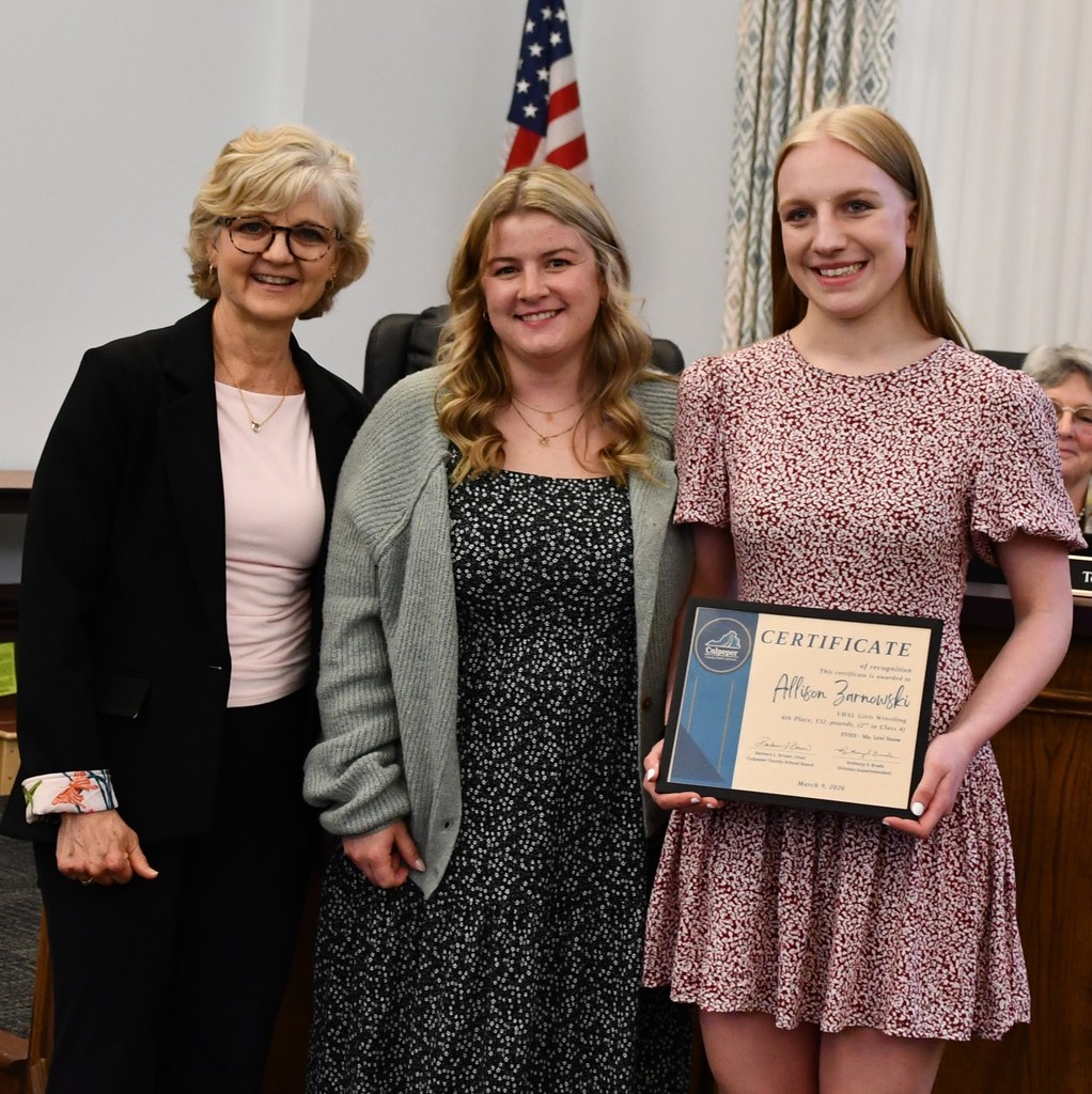 student holding certificate in board room with coach and board member