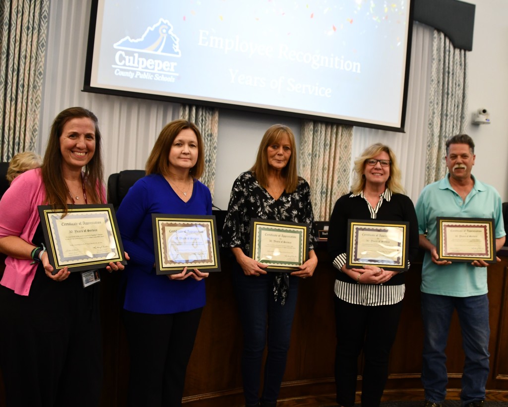 group of 5 adults holding certificates in board room
