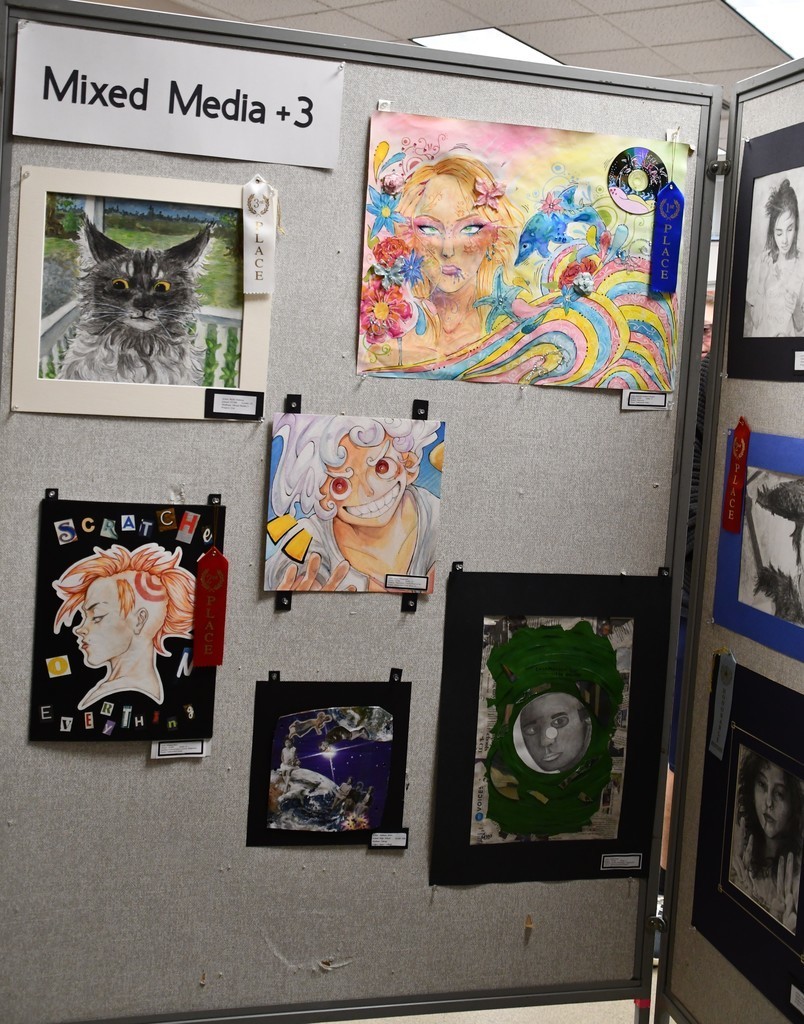 a board showing student artwork with ribbons on it
