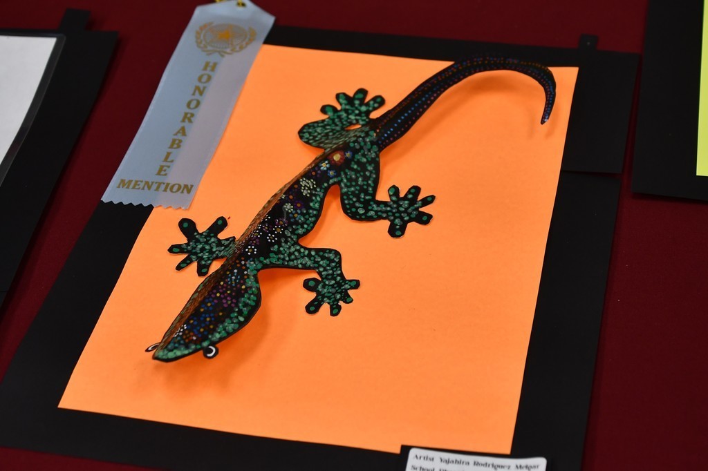a sculpture of a lizard on an orange background with a riboon on it 