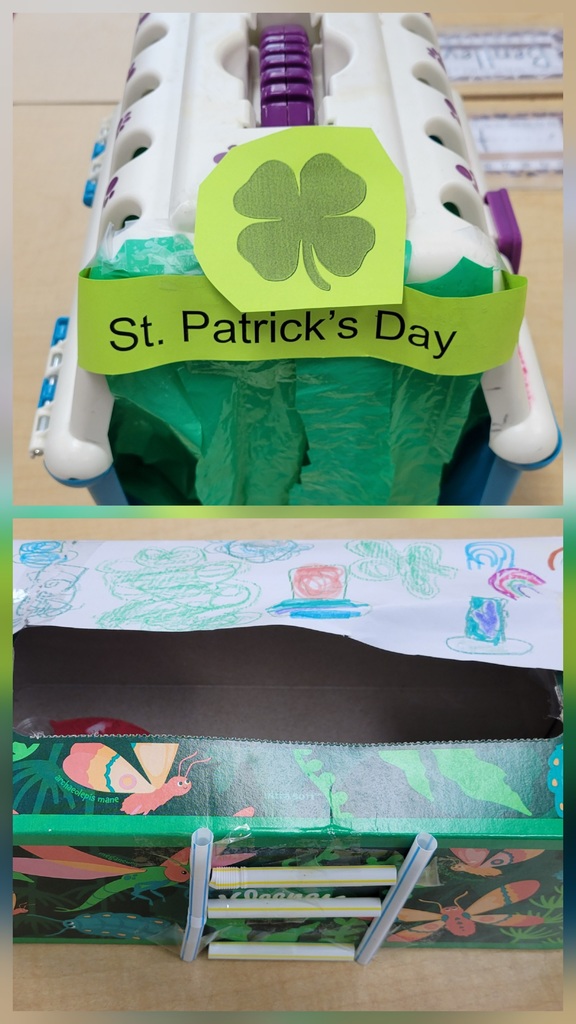 A container labeled “St. Patrick’s Day” with a shamrock sits on a table. Below, a decorated box with insect-themed paper and a drawn scene on top includes a small ladder leading inside.