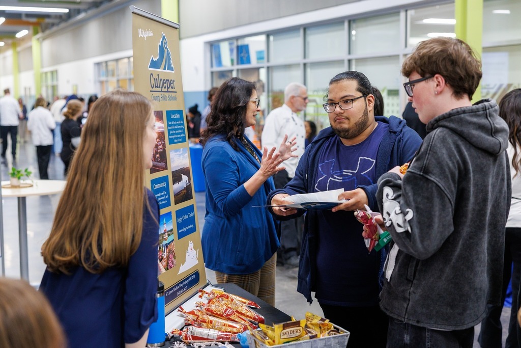 Students speak with a Culpeper County Public Schools representative at a table during a senior job fair.