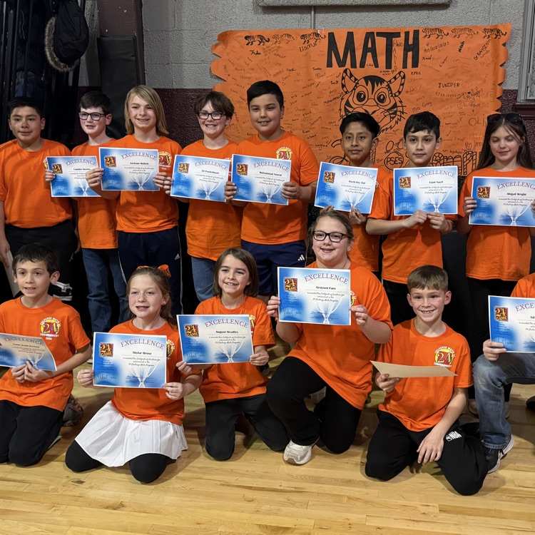 24 Math competition students standing in front of an orange and black banner holding certificates l.