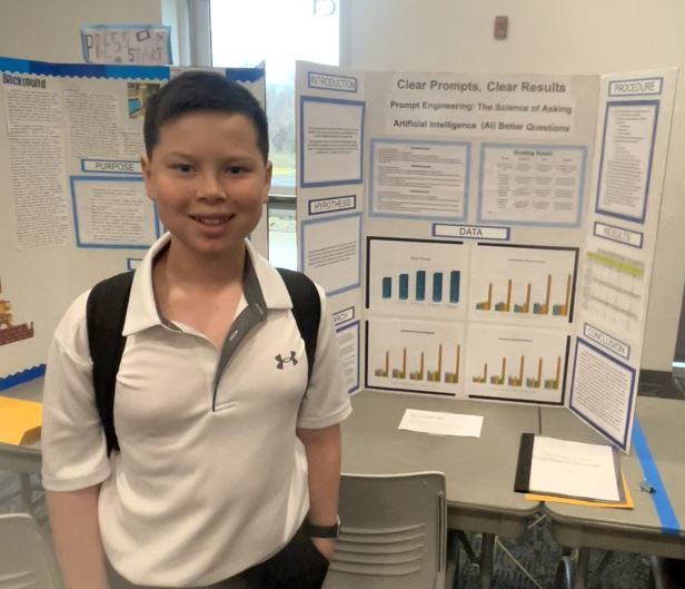 Student stands in front of a project titled “Clear Prompts, Clear Results,” featuring charts and data about prompt engineering and artificial intelligence.