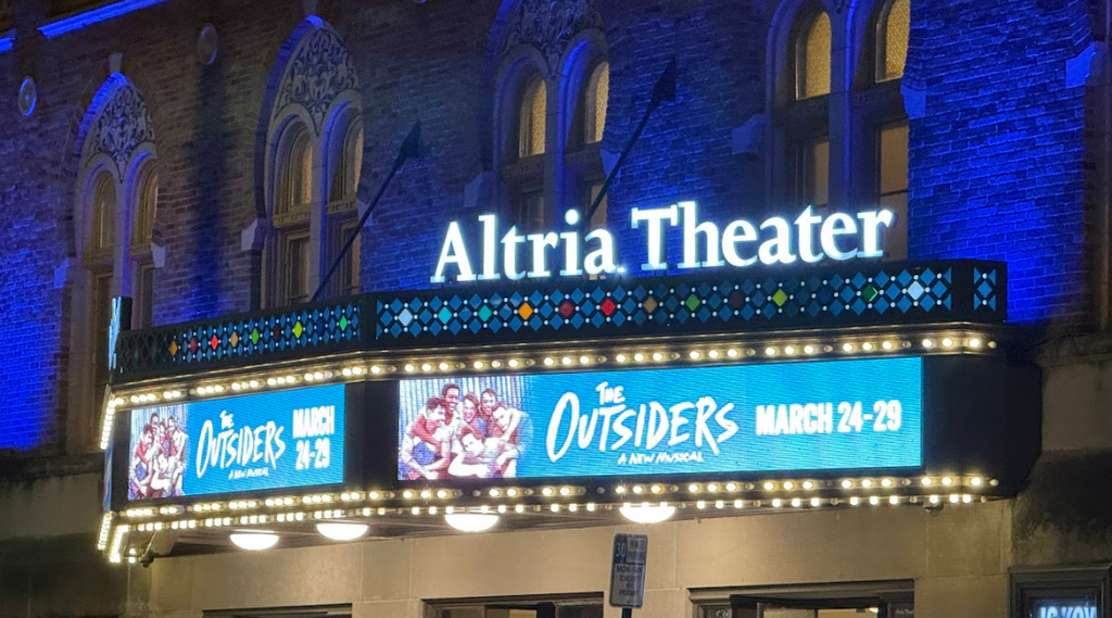 Marquee of the Altria Theater in Richmond lit at night, displaying “The Outsiders” musical with show dates.