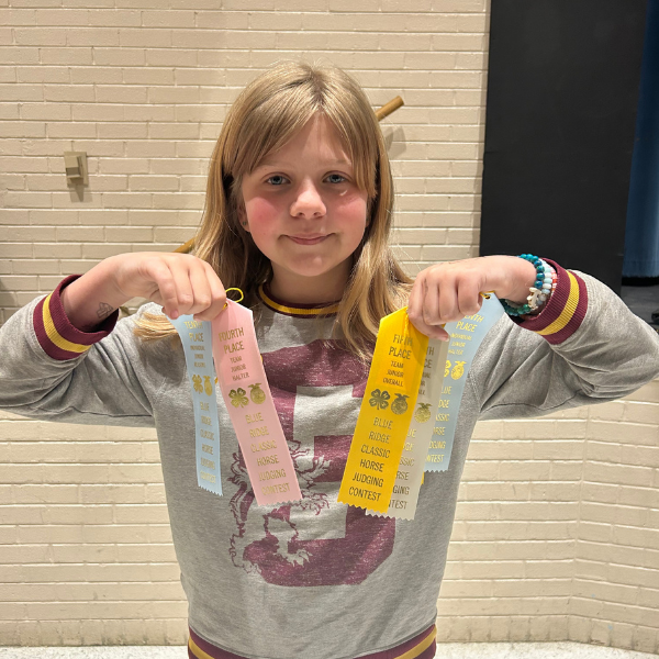 A student stands indoors holding several award ribbons from the Blue Ridge Classic Horse Judging contest, showing her individual placements.