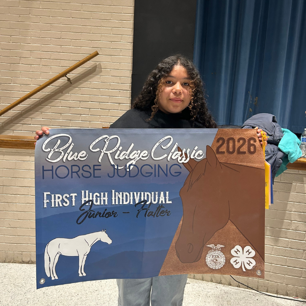 A student stands indoors holding a large Blue Ridge Classic Horse Judging banner recognizing first high individual in the junior halter division.
