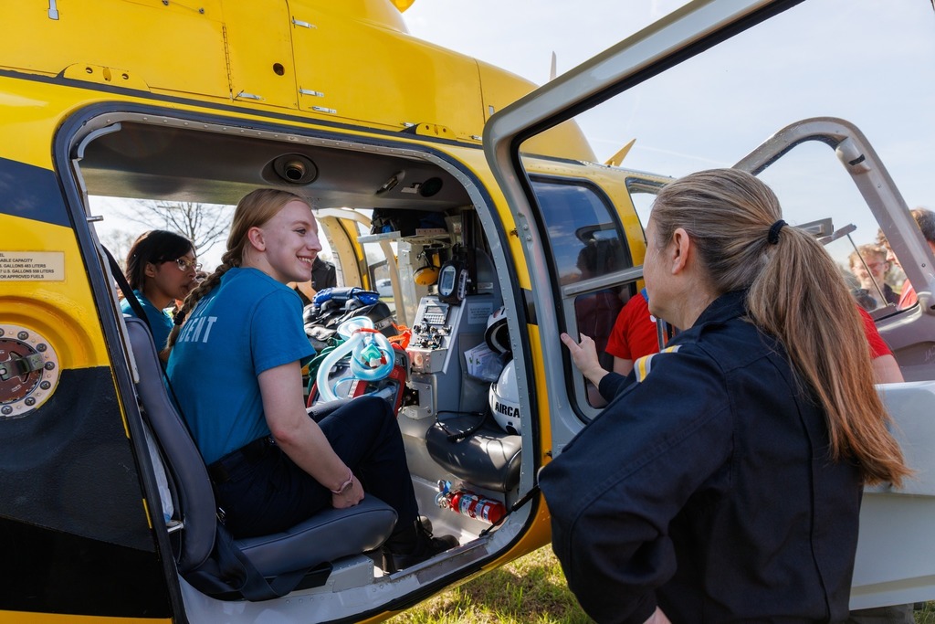 CTEC EMT students explore the interior of the AirCare 6 medical helicopter, sitting inside the aircraft and speaking with a flight crew member while viewing onboard emergency equipment.