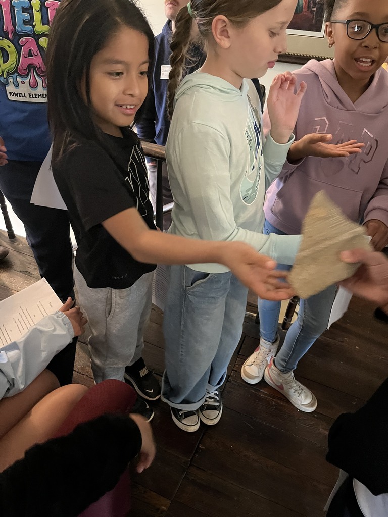 Students pass around and examine a small artifact while standing together indoors.