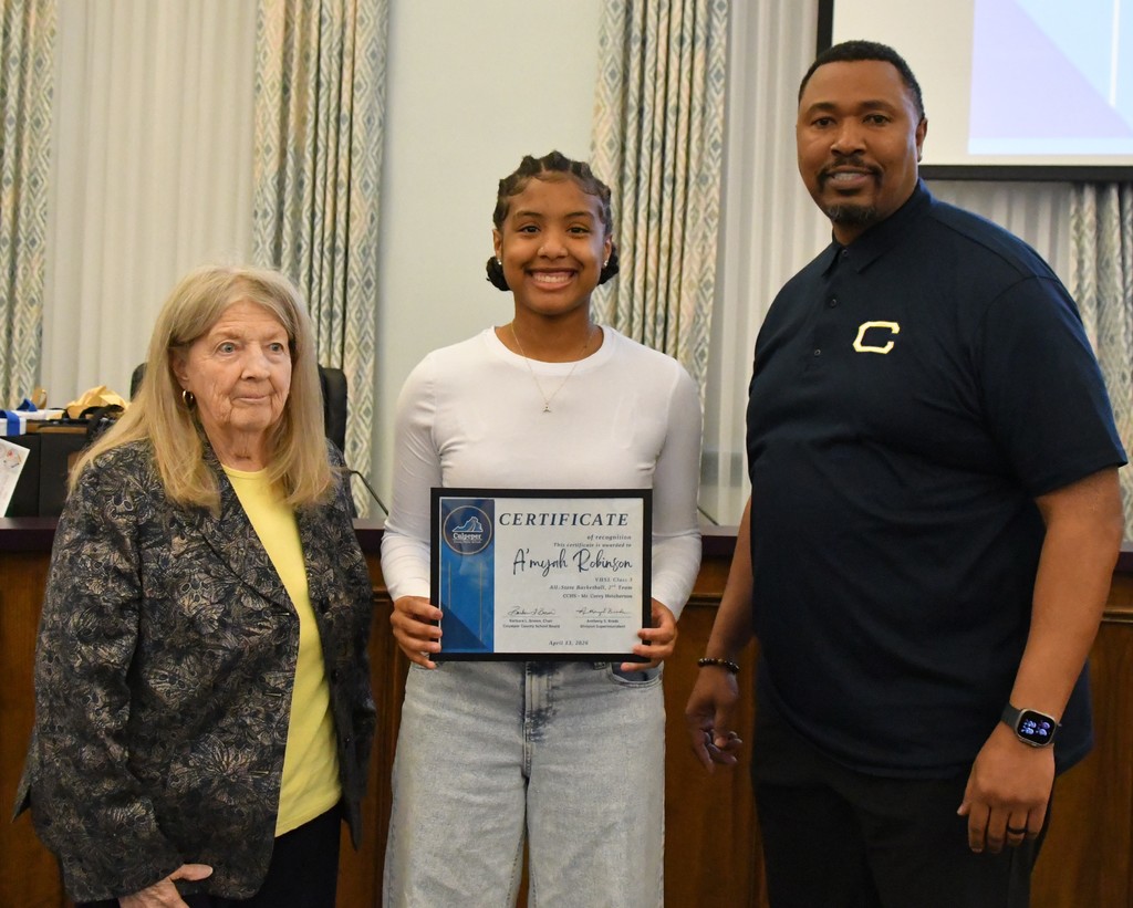 student holding certificate with coach and board member in board room