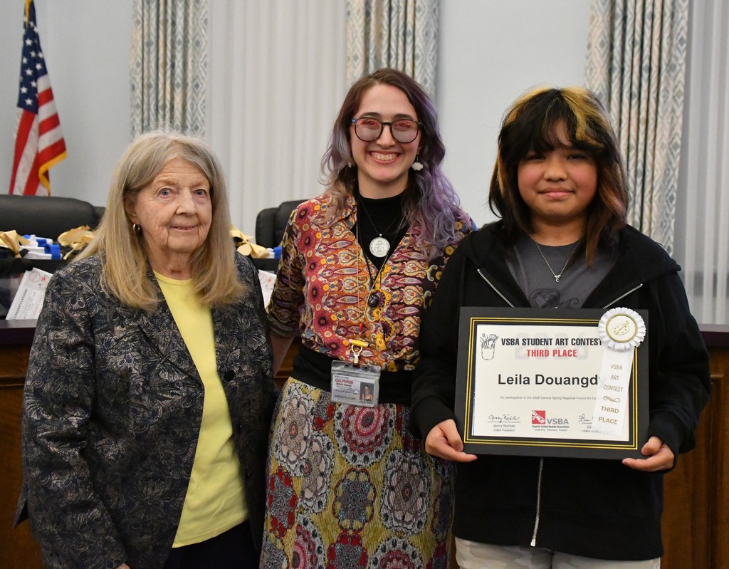 student holding certificate with teacherand board member in board room