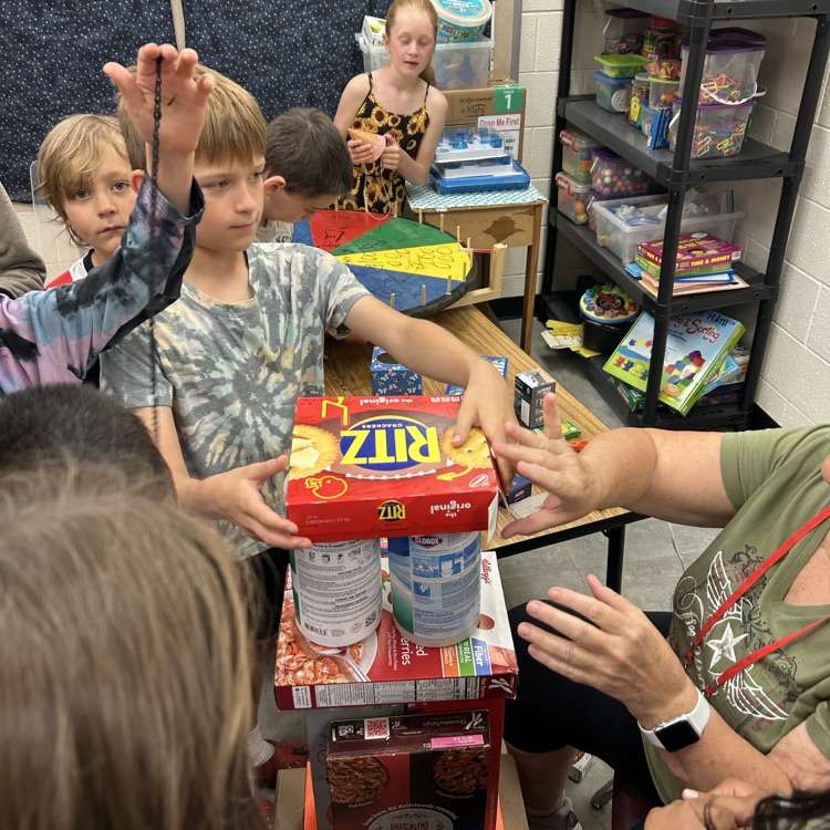 students work together with the help of a teacher balancing 3d shapes