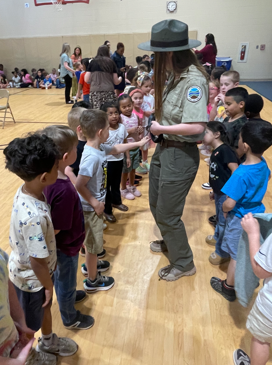 A wider view shows a long line of students in a gym waiting to interact with the ranger and the snake.