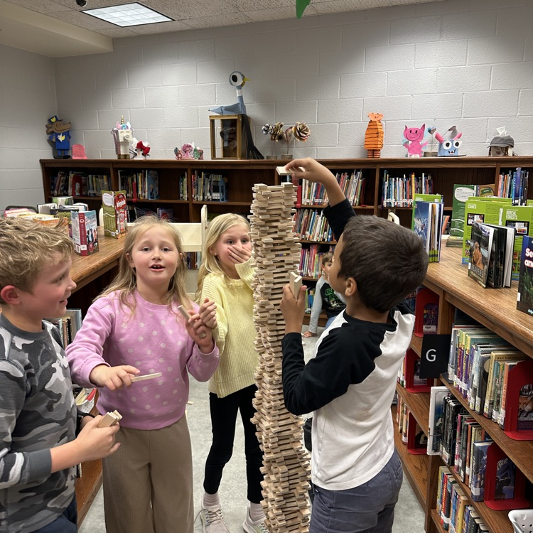 students pictured standing around a stack of keva planks taller themselves 
