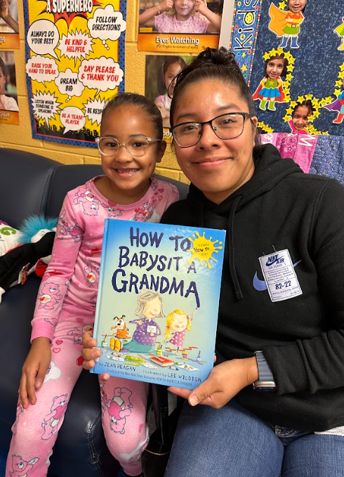 Adult and child sit together smiling and holding a book titled “How to Babysit a Grandma.”