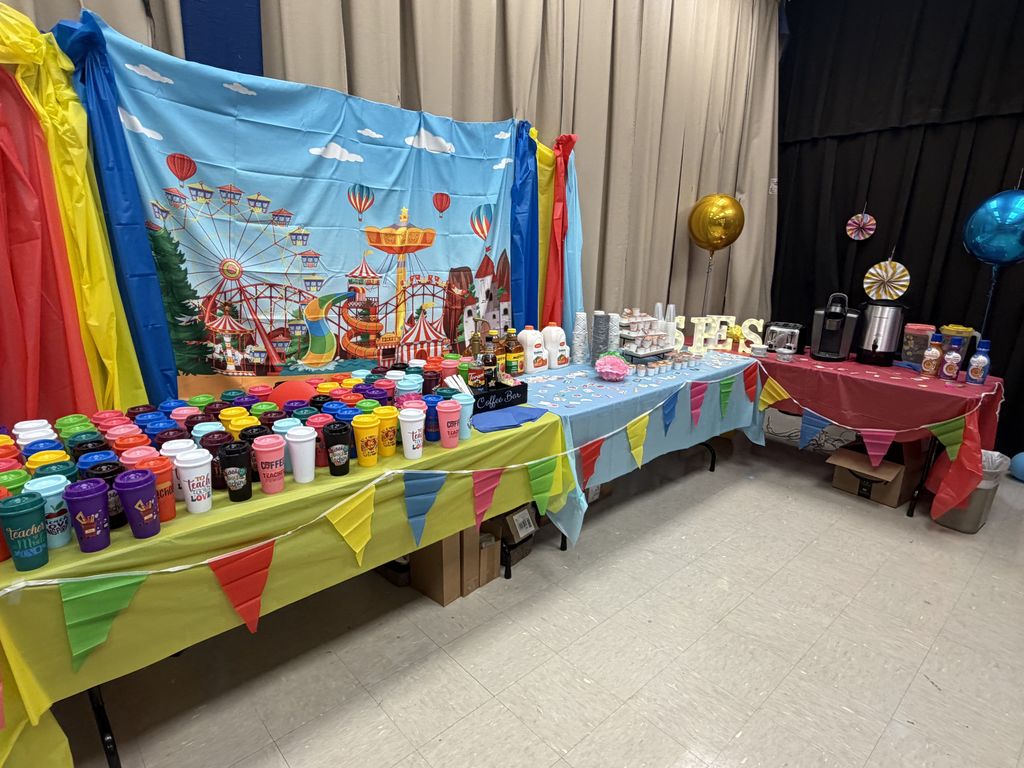 A room with colorful decorations, balloons, and tables. Tables have many colorful cups and other items.