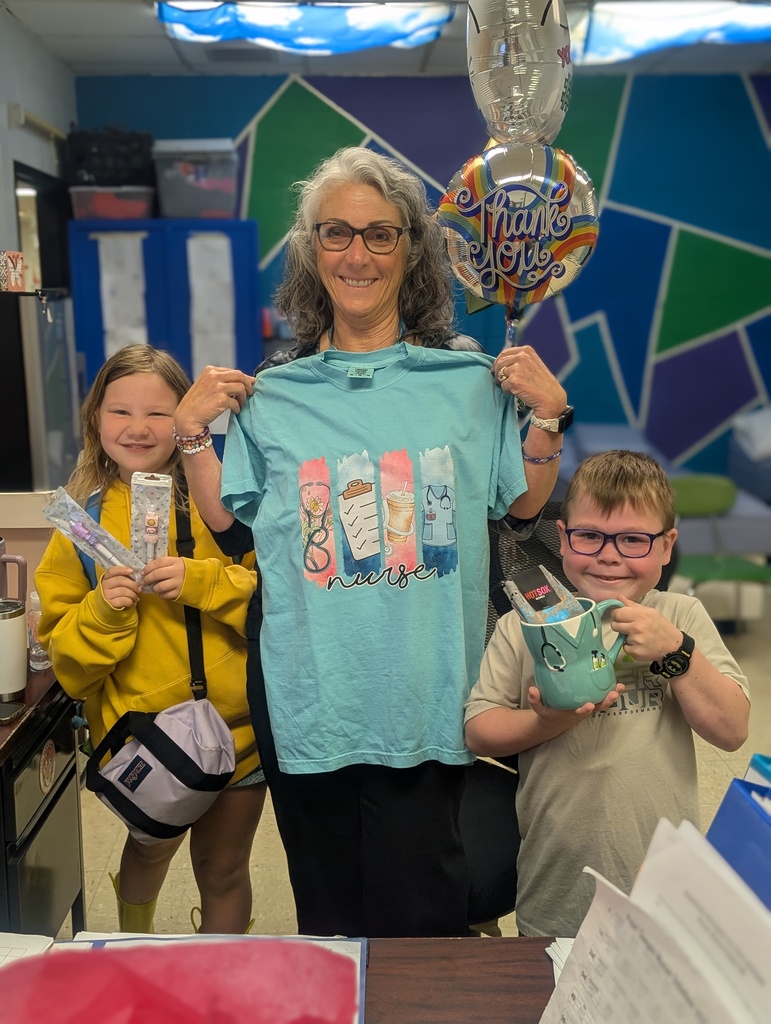 A woman in glasses and a blue t-shirt stands with two children. They hold gifts and balloons.