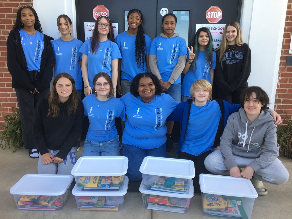 A group of young people in blue shirts are posing for a photo with several clear plastic containers.
