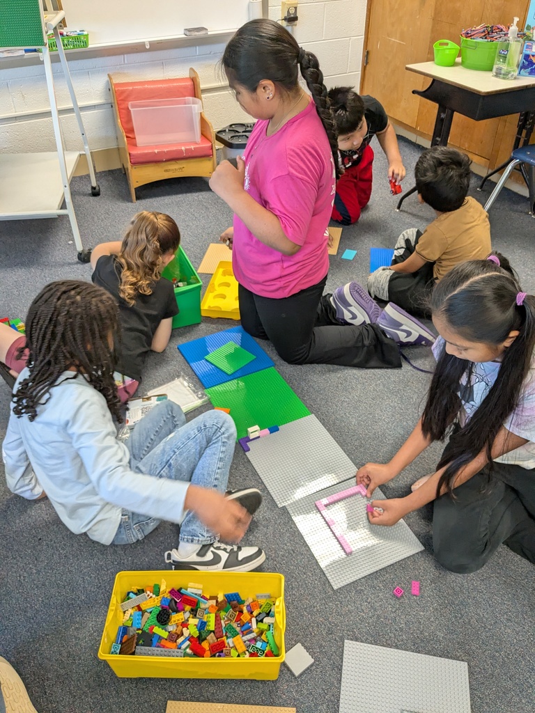 A classroom with children sitting on the floor, engaged in activities with colorful building blocks.