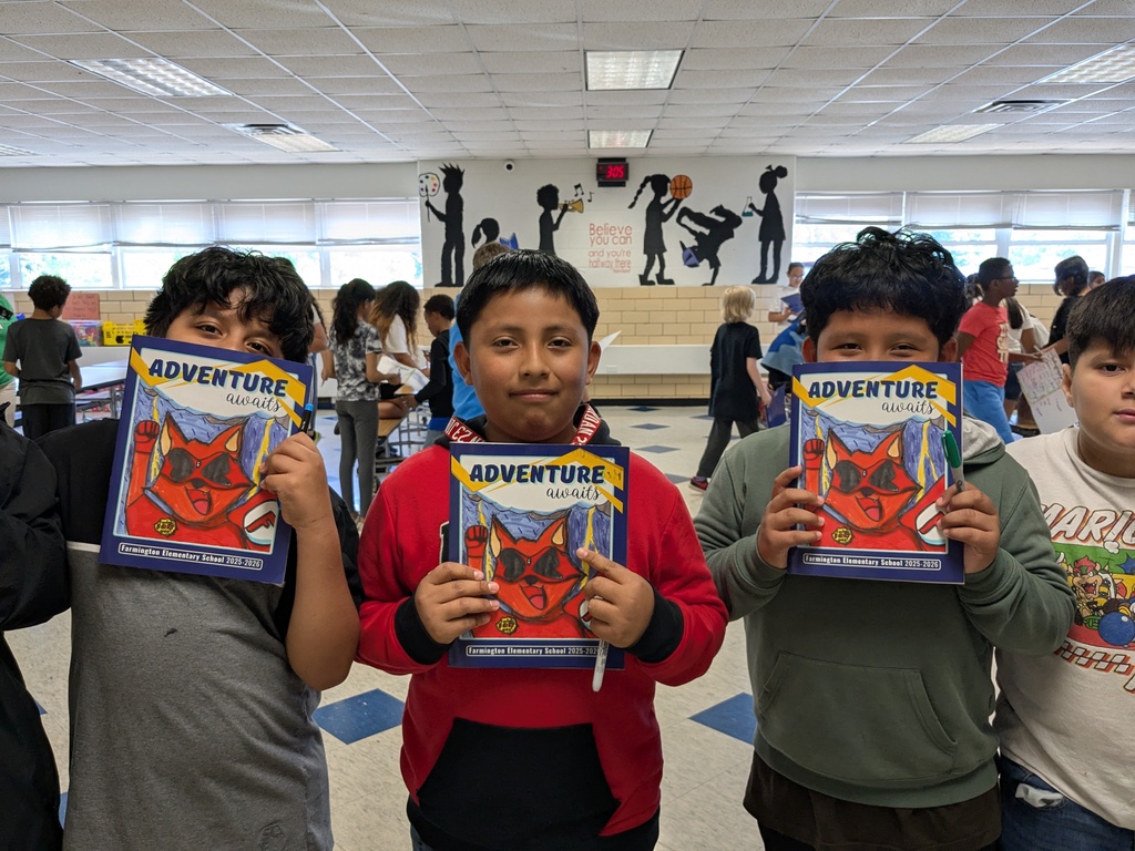 Four boys in a room with a mural on the wall, holding books with a red cat on the cover.