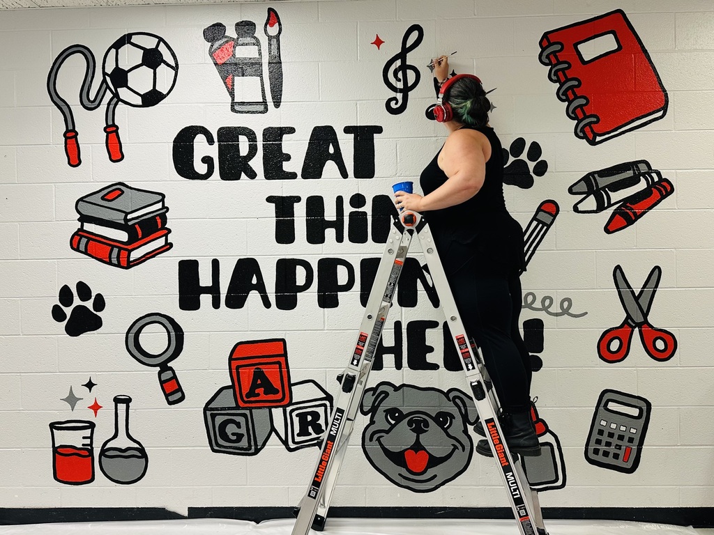Adult on ladder adding finishing touches to a mural that says great things happen here