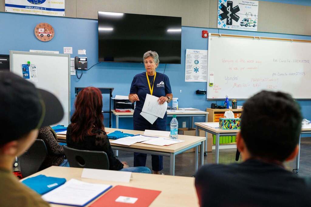 An Emergency Medical Technician (EMT) instructor leads an orientation session, speaking to students gathered in the classroom as they review course materials and prepare for the start of the program.