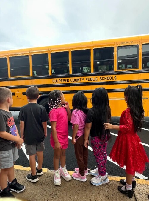 A row of children in front of a yellow school bus with text reading "Culpeper County Public Schools".