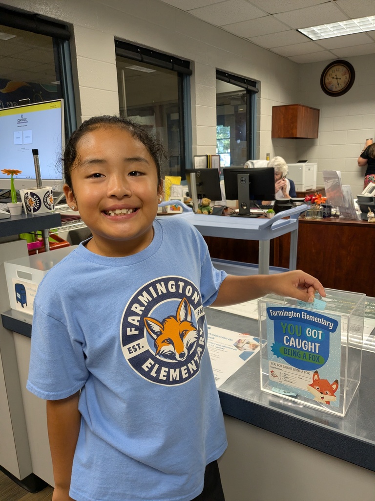 Child wearing blue Farmington Elementary shirt holds a clear box with "You Got Caught" text.