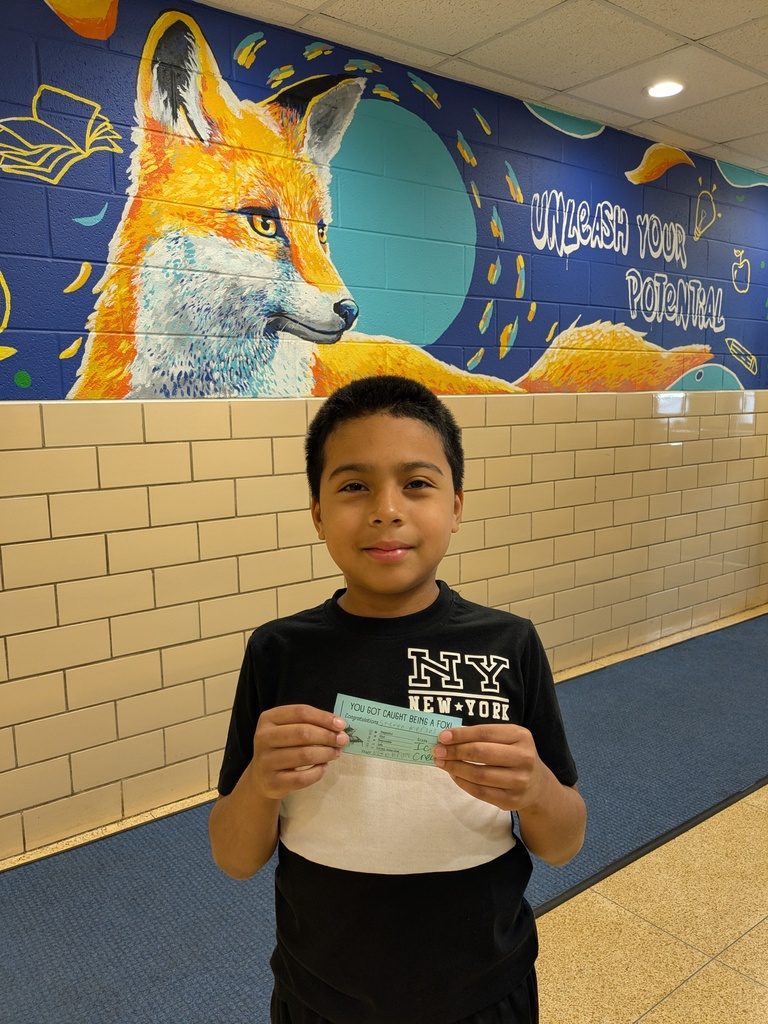 A boy in a black and white shirt holding a ticket stands in a hallway with a mural of a fox.