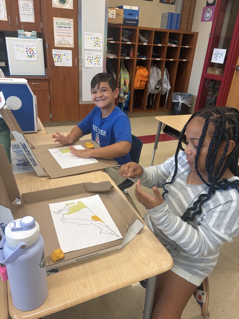 Two students work with colorful modeling clay to build Virginia’s geographic regions on paper maps inside pizza boxes.