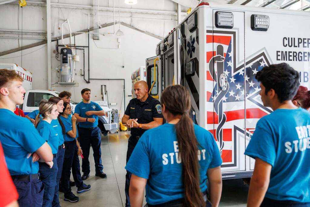 CTEC EMT and Firefighter students tour an emergency services facility as a Culpeper County emergency services lieutenant speaks to the group beside an ambulance.
