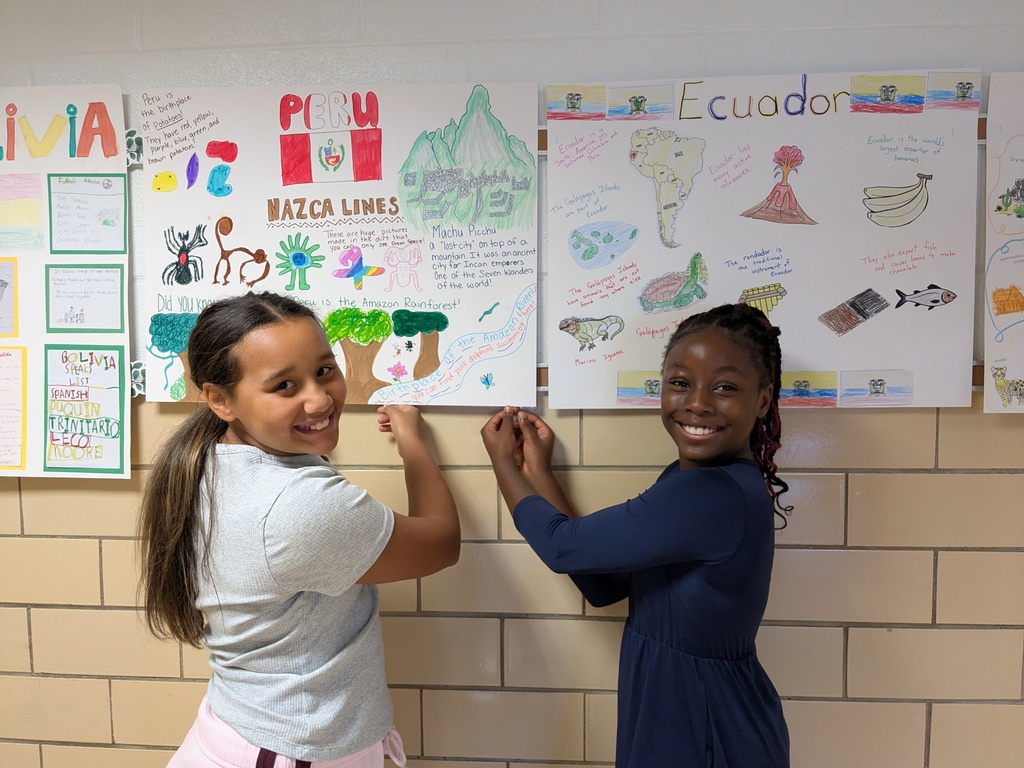 Student on left is helping student on the right hang posters for Hispanic Heritage Month