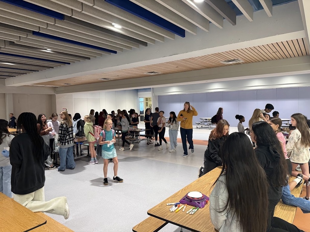 CMS students fill the cafeteria during International Dot Day, gathering around tables with markers and activity materials as they celebrate creativity and making their mark.
