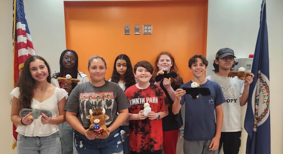Eight CMS students pose together after successfully reciting the Preamble from memory for the Constitution Day Challenge. Several students proudly hold patriotic eagle and plush prizes they won as part of the celebration.