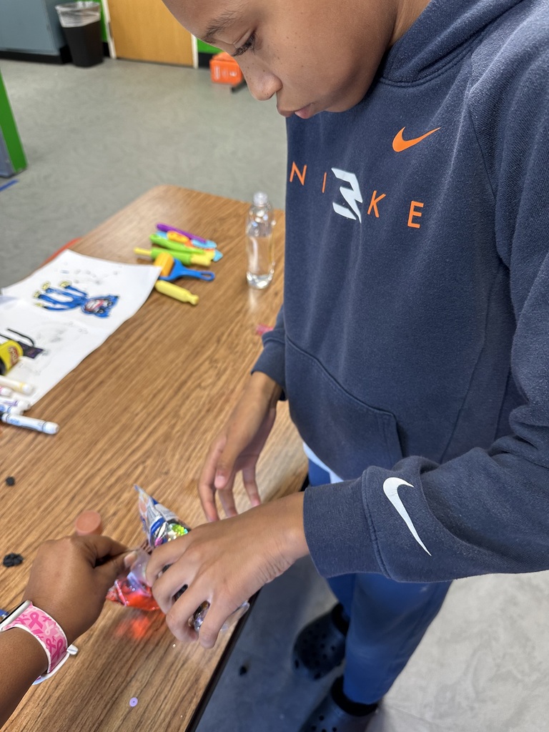 A person in a blue Nike hoodie opens a plastic package on a wooden table.