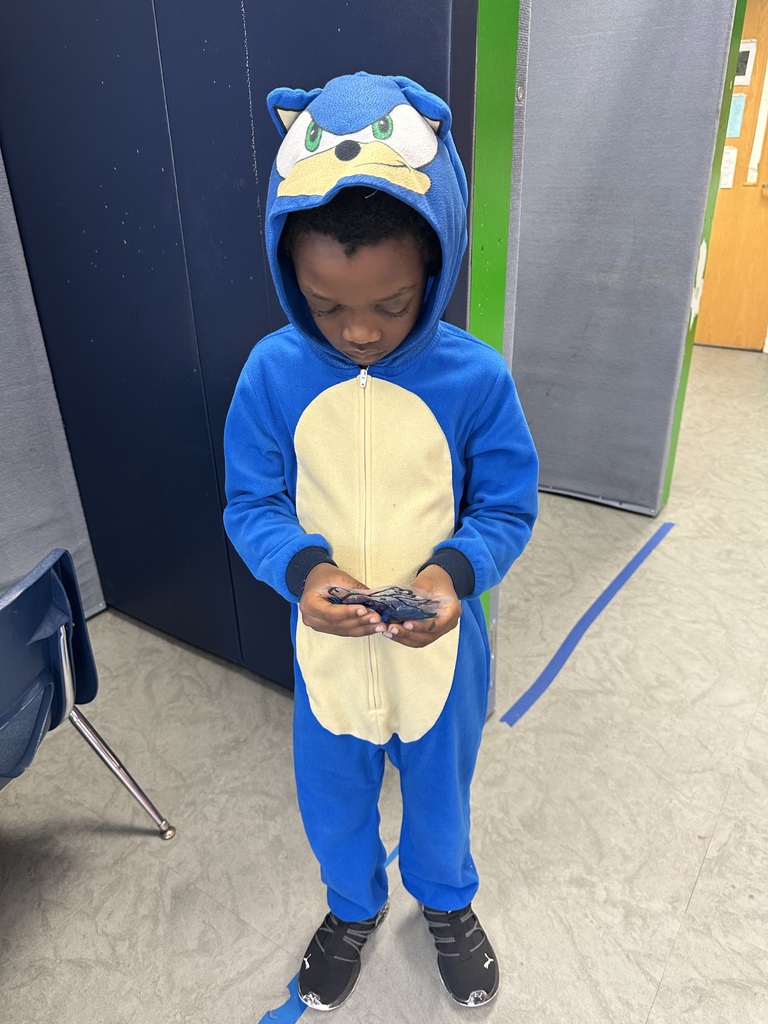 A child in a blue Sonic the Hedgehog costume, looking down at a handheld game device.