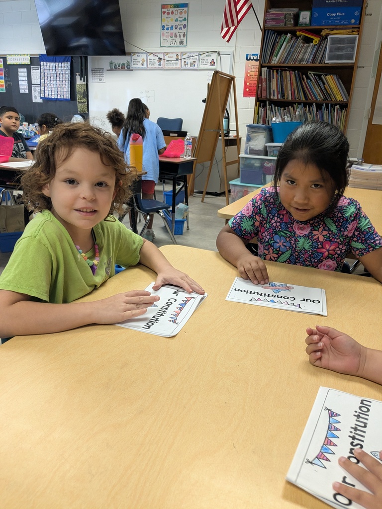 Students sit around a table reading their Our Constitution books.
