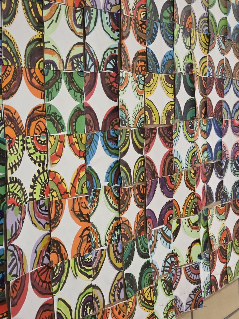Wall covered with many colorful circular art pieces in various patterns. Each circle is a unique artwork.
