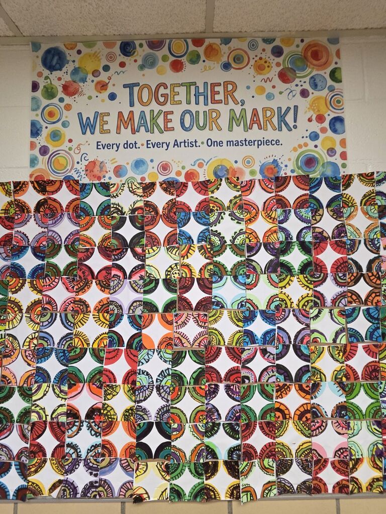Colorful circles form a pattern on a wall with a motivational quote above. Background is plain white with white ceiling tiles.