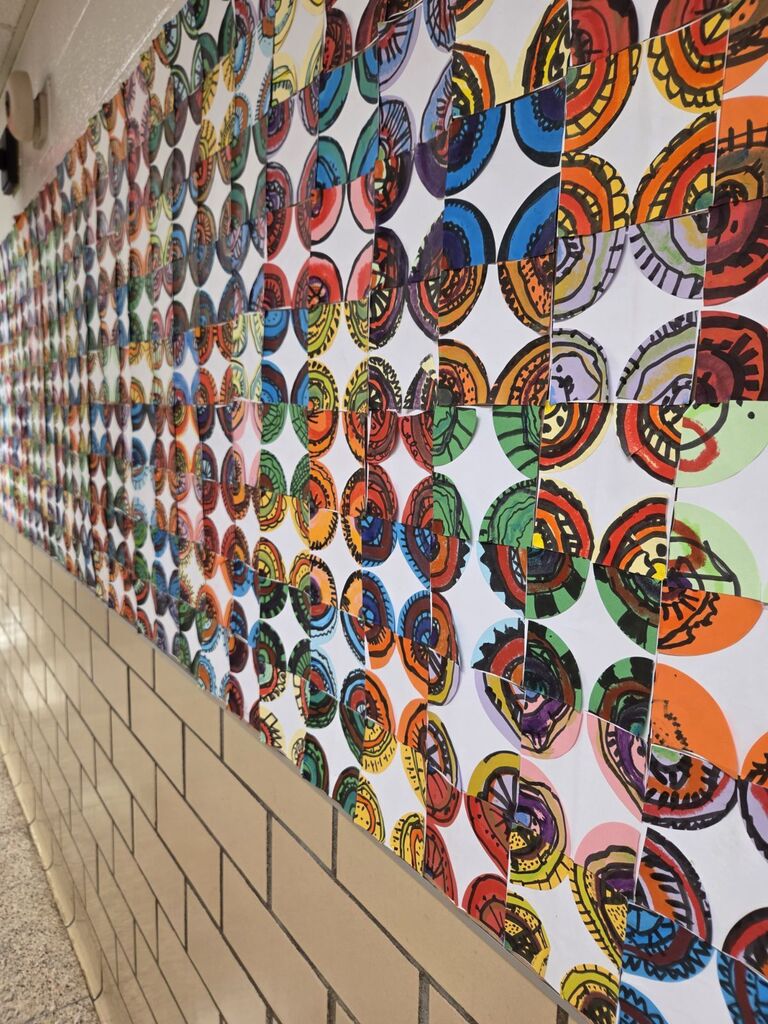 A hallway wall covered with a series of colorful, circular artworks. Each circle features unique designs.