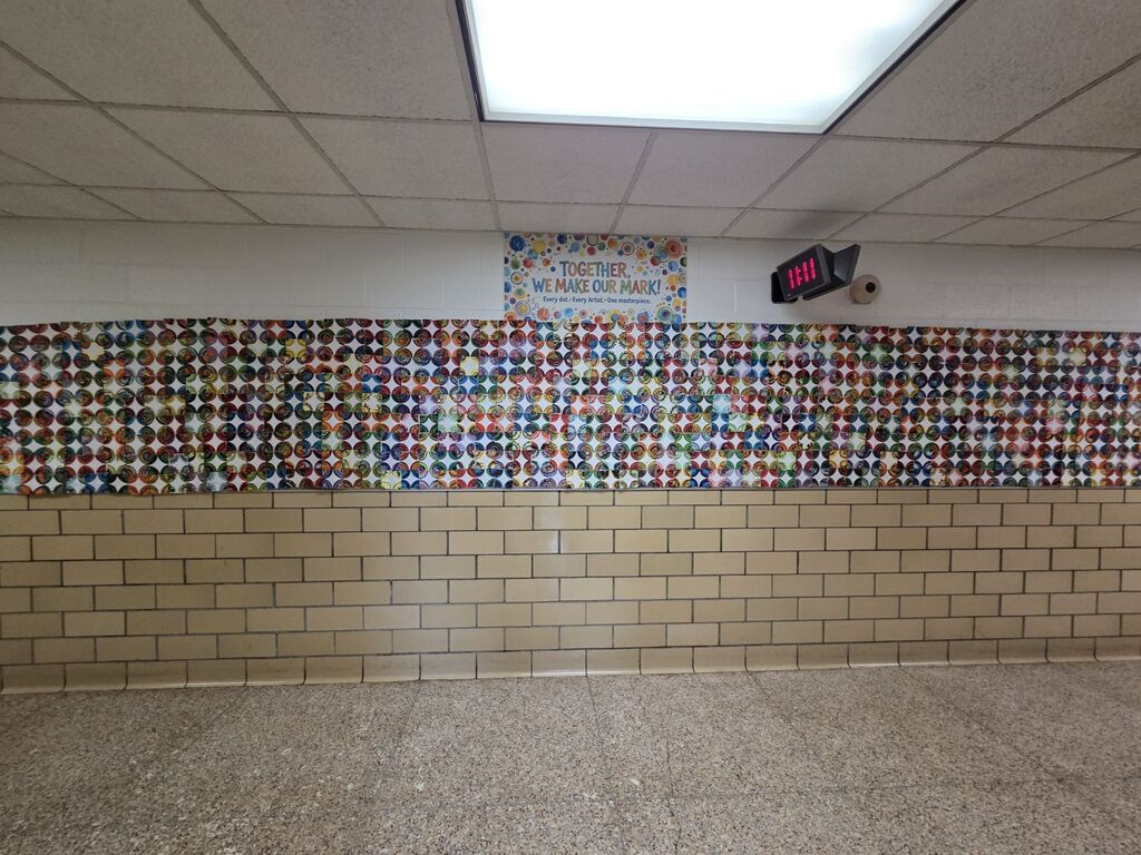 An empty room with a patterned wall and a brick base. A sign hangs on the wall. The ceiling has a fluorescent light.