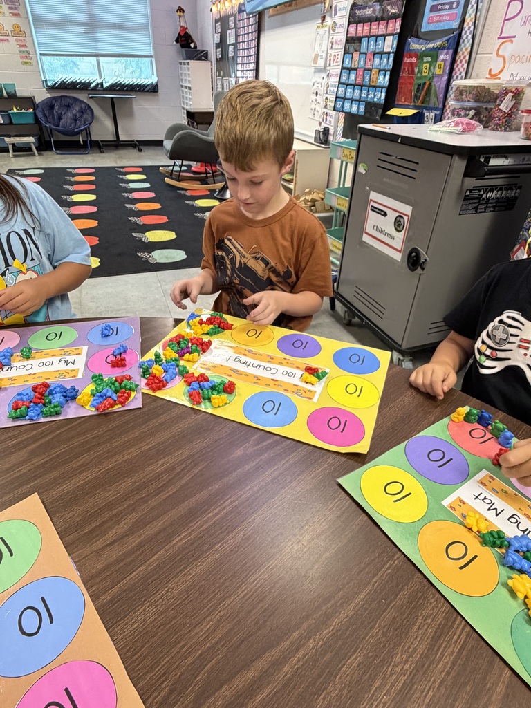 A classroom where children engage with colorful educational materials. One child sits at a table, using colorful building blocks.
